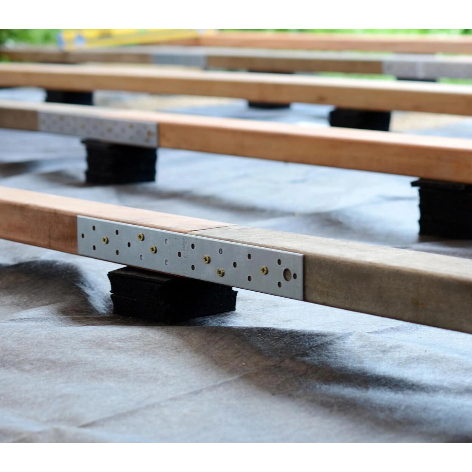Terrassenpads unter Holzbalken einer Terrasse zur Trittschalldämmung und als Unterkonstruktion.