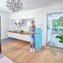 Frau hält Leifheit Bügeltisch AirBoard Compact M Plus mit blauem Bezug. Kompaktes, höhenverstellbares Bügelbrett.
