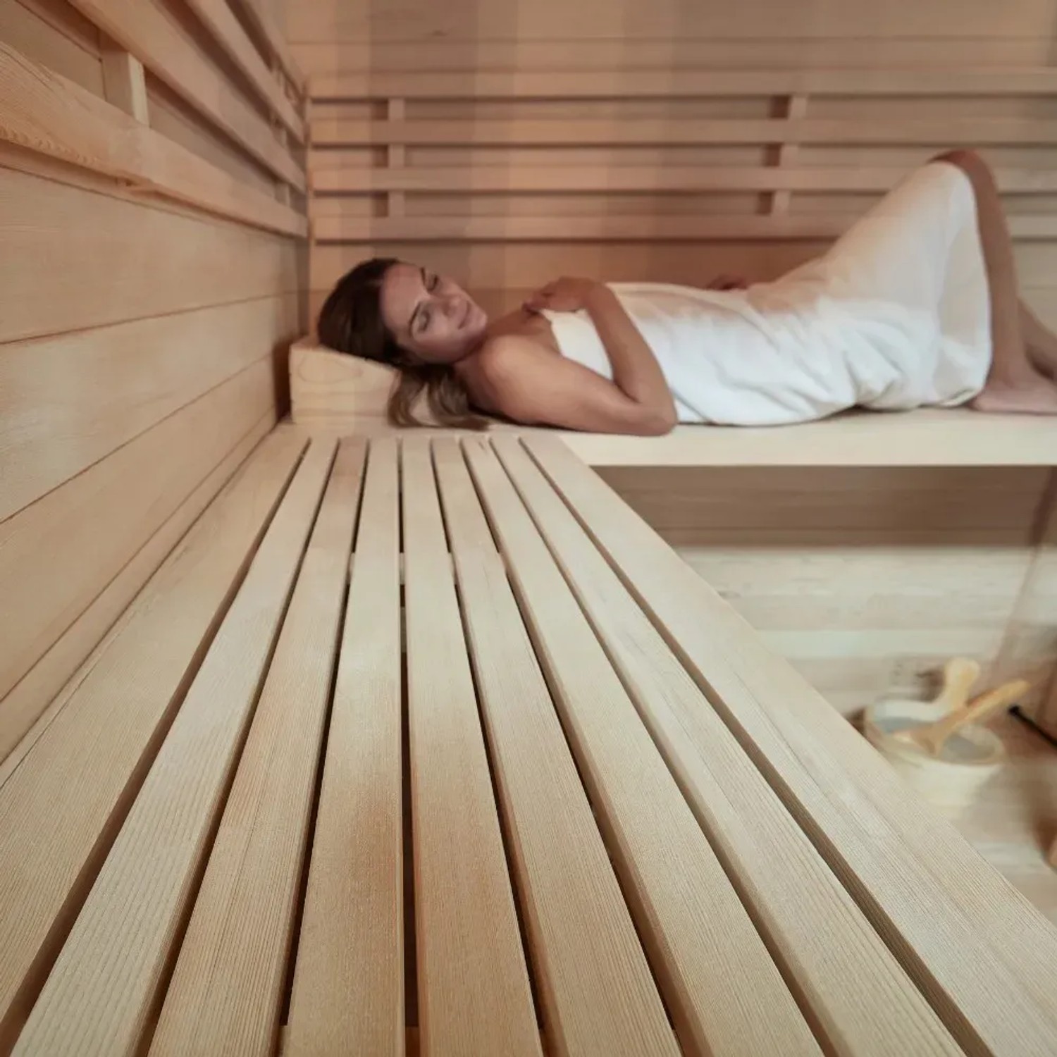Frau entspannt in der SKYLINE BIG Sauna aus Tannenholz. Massivholzsauna mit Liegebänken und Zubehör.
