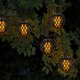 Näve LED Solar Lichterkette Fogo mit Flammeneffekt, schwarze Kugeln an einem Baum.