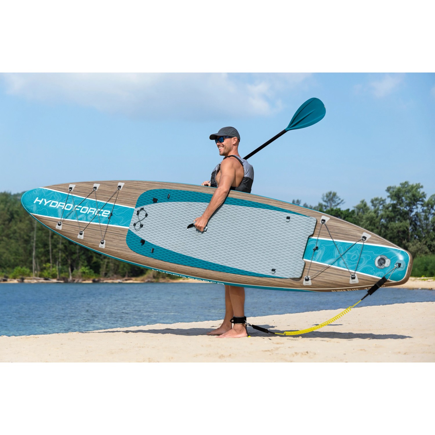 Mann trägt Bestway SUP Touring Board Glider Elite mit Paddel am Strand.