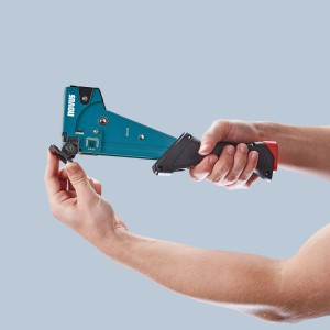 Novus Hammertacker J-055, blauer Tacker für Flachdrahtklammern Typ G, in der Hand gehalten.