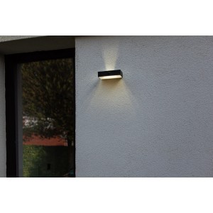 Schwarze Lutec LED Solar Wandleuchte Fadi mit Bewegungsmelder an grauer Hauswand.