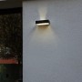 Schwarze Lutec LED Solar Wandleuchte Fadi mit Bewegungsmelder an grauer Hauswand.