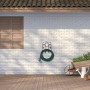 Schwarzer Stahl Gartenschlauchhalter an weißer Wand mit grünem Schlauch. Platzsparende Wandmontage für Garten & Garage.