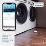 Homematic IP Wassersensor SWD-2 am Boden neben Waschmaschine, Smartphone zeigt Wasser-Alarm in der App. Smart Home Hausautomation.