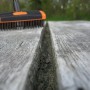 Fugenbürste reinigt Fuge auf Holzterrasse. Set mit Teleskopstiel und 2 Aufsätzen.
