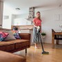 Frau saugt mit Kärcher Akku-Staubsauger VC 4 Cordless myHome Holzboden im Wohnzimmer.
