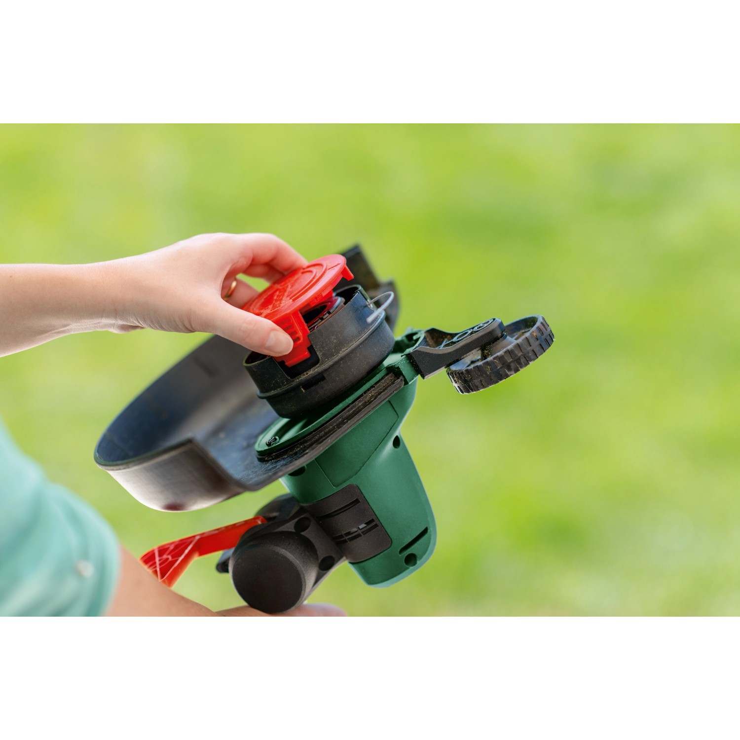 Bosch Akku-Rasentrimmer UniversalGrassCut 18V-26: Hand wechselt Spule des Akku-Trimmers.