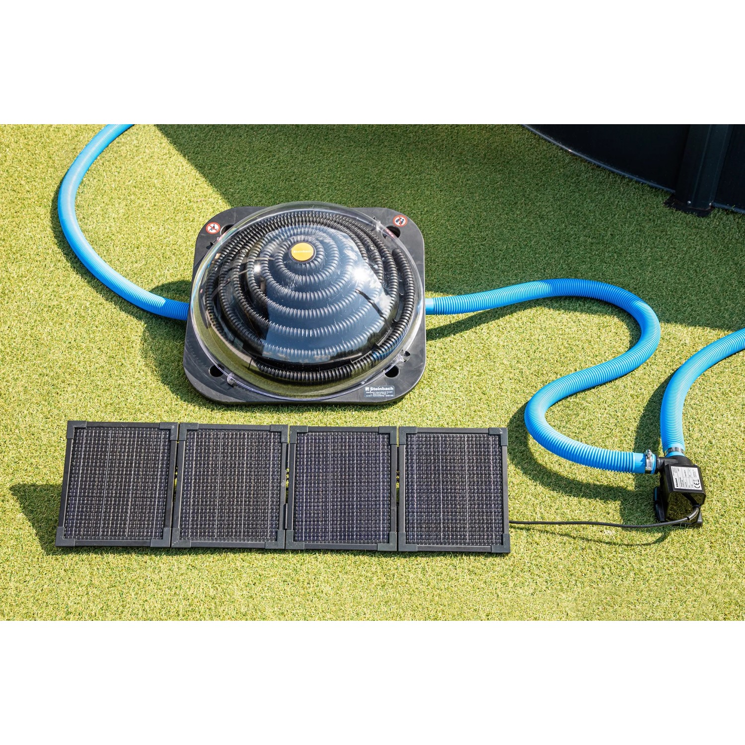 Steinbach Zirkulationspumpe mit PV-Panel zur Poolerwärmung, mit blauen Schläuchen und Solarpanel auf Rasen.