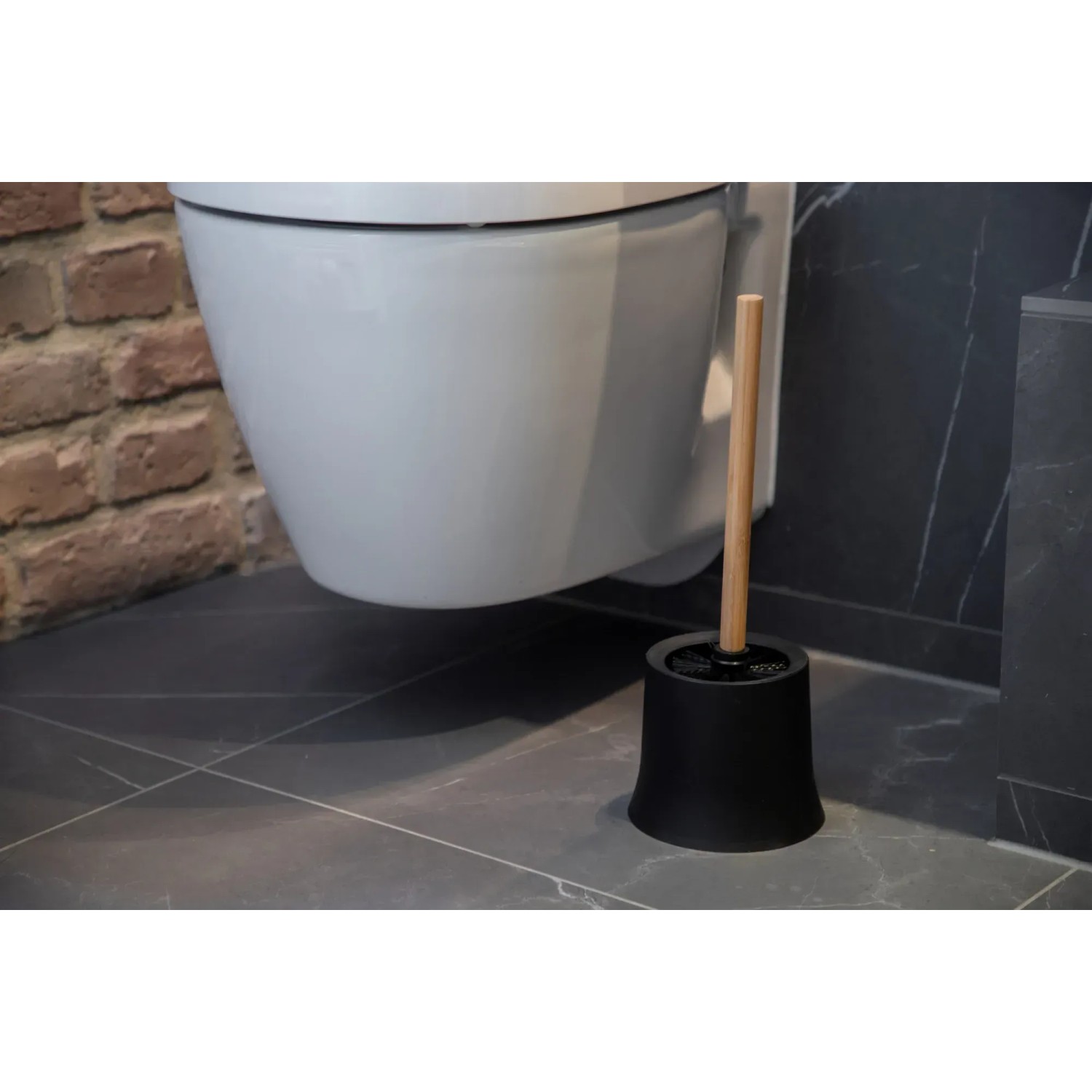 Wenko WC-Garnitur Basic Bambusa mit schwarzem Behälter und Bambus-Stiel vor einer Toilette.