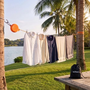 Orange ausziehbare Wäscheleine mit Kleidung zwischen Palmen am See; Reisewäscheleine für Camping & Outdoor.