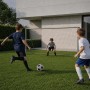Drei Jungen spielen Fußball im Garten mit einem grauen Stahl-Fußballtor. Robustes Sport & Fitnessgerät.