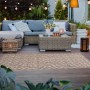 Brauner Primaflor In- und Outdoorteppich (160x220cm) mit Zickzackmuster auf Terrasse mit Möbeln.