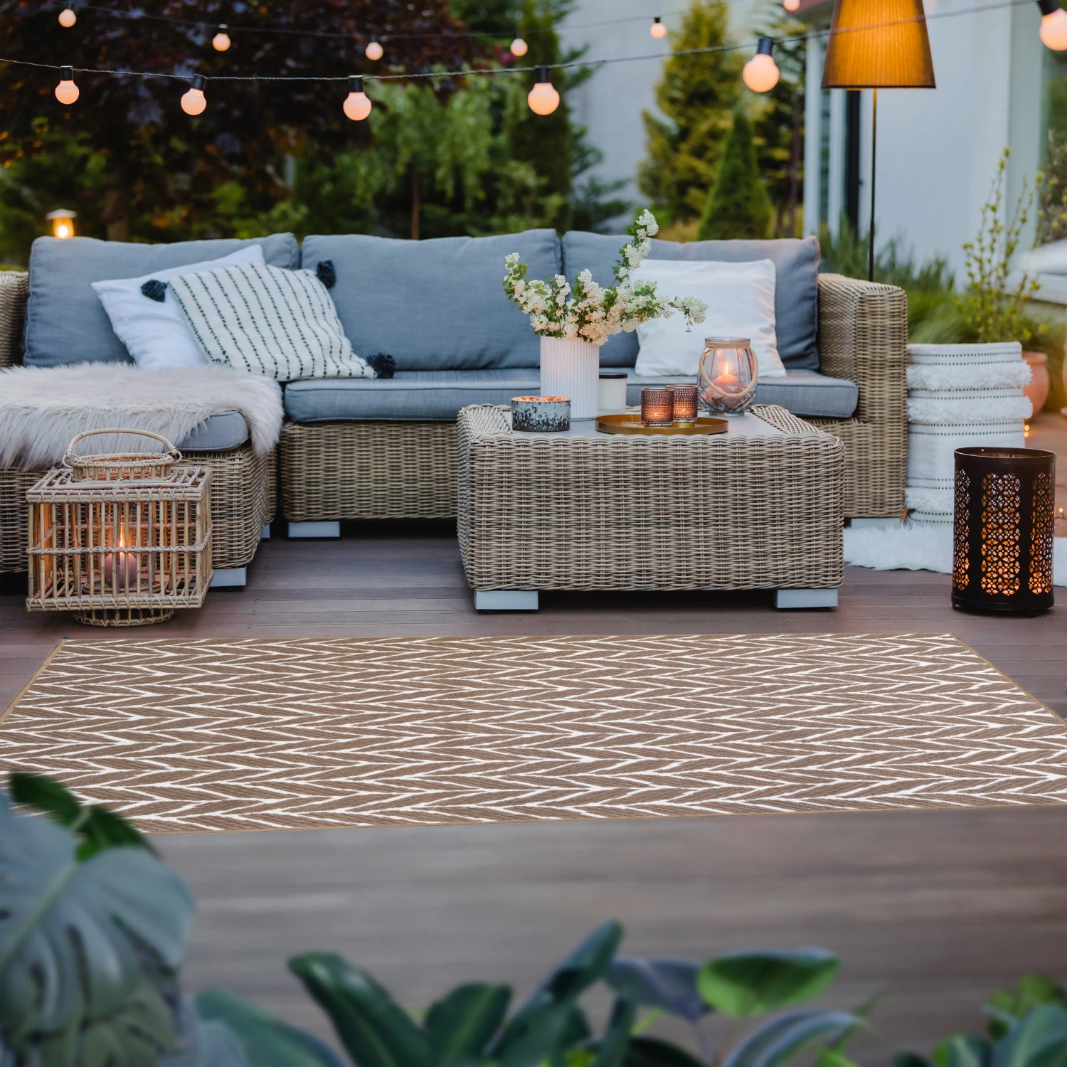 Brauner Primaflor In- und Outdoorteppich (160x220cm) mit Zickzackmuster auf Terrasse mit Möbeln.