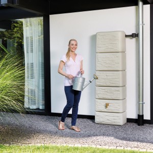 4rain Zisterne Slim Stone Decor Regentonne in Sandbeige (330 l) mit Frau und Gießkanne.