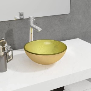 Modernes goldenes Hartglas-Waschbecken auf weißer Arbeitsplatte im Badezimmer. Rundes Aufsatzwaschbecken mit glänzendem Finish.