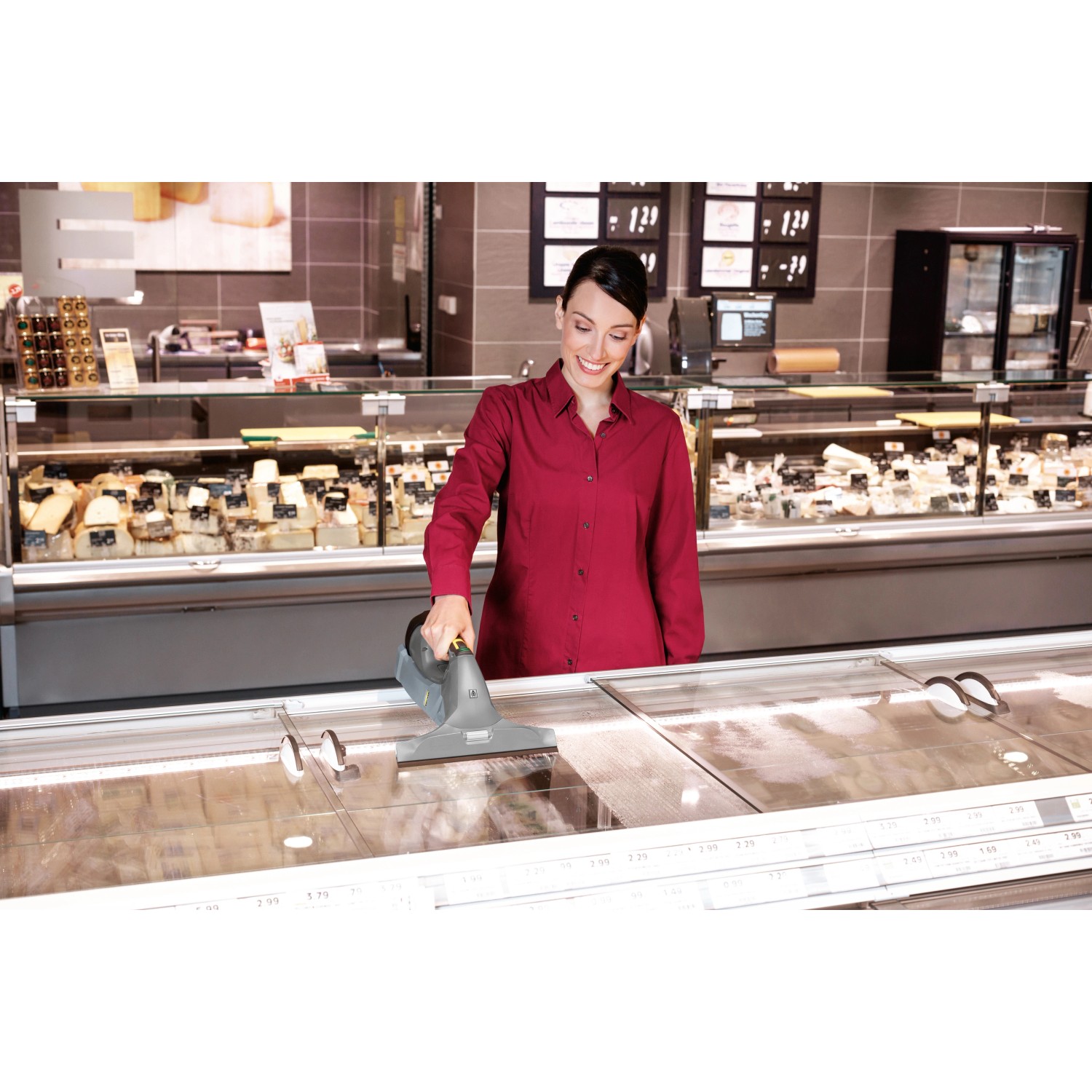 Frau reinigt Kühltheke mit Kärcher Fenstersauger WVP 10 für streifenfreie Sauberkeit.