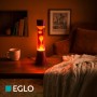 Eglo LED-Lavatischleuchte Bordeaux/Orange auf Holztisch. Weinrote Flüssigkeit, orangefarbenes Wachs leuchtet warm.