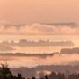 Komar Vlies Fototapete Chiemsee: Landschaft mit See und Nebel in sanften Farben.