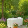 Weißer, rechteckiger KMND 300L Trinkwasser Wassertank im Garten auf gepflastertem Untergrund, umgeben von Blumen und Bäumen.