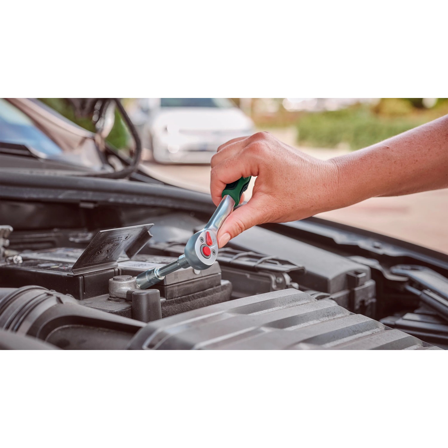 Bosch Steckschlüsselsatz im Einsatz: Hand schraubt mit Ratsche am Auto.