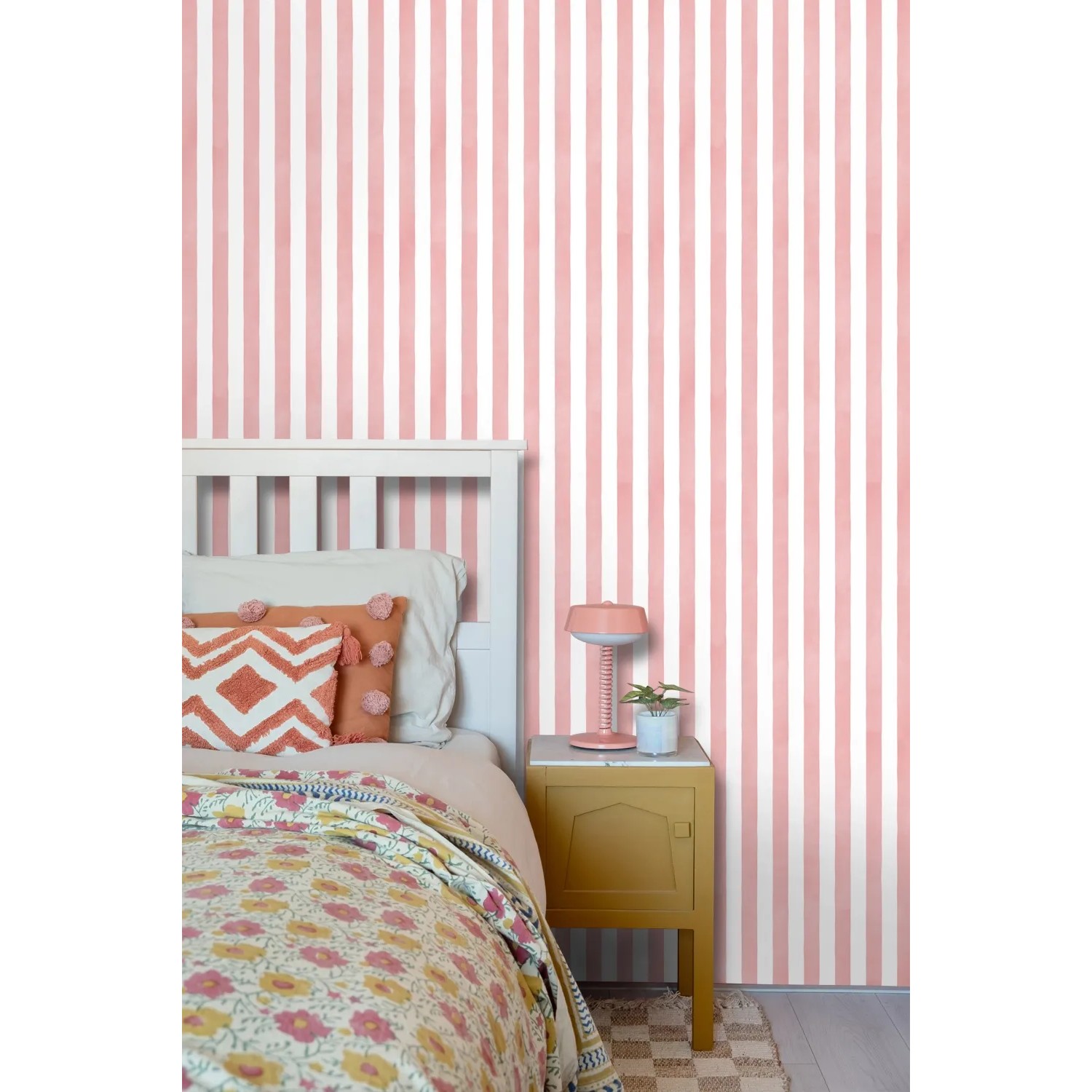 ESTAhome Vliestapete mit rosa-weißem Streifenmuster an einer Wand, daneben ein weißes Bett. Dekorative Tapete.