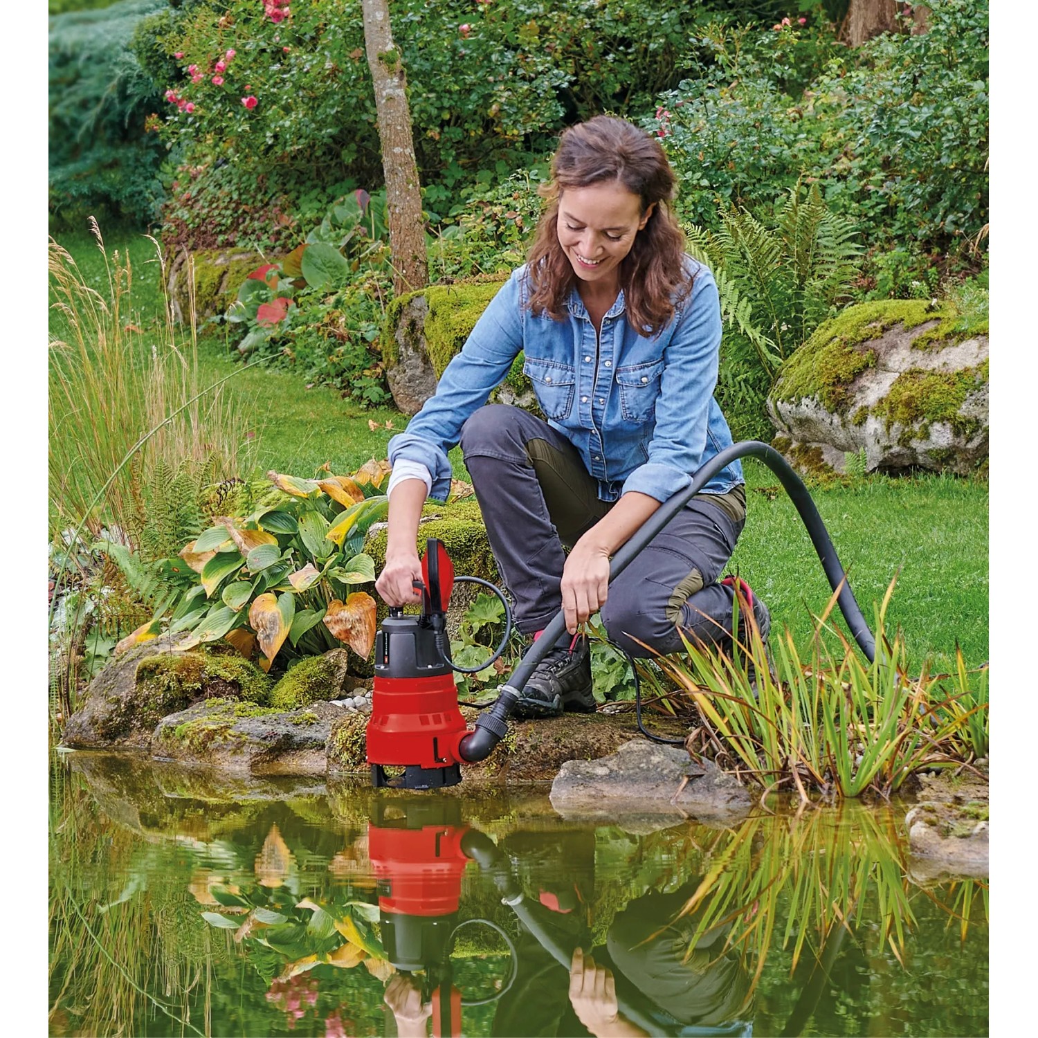 Einhell GC-DP 6935 LL Schmutzwasserpumpe im Einsatz am Gartenteich. Elektro-Pumpe mit rotem Gehäuse.