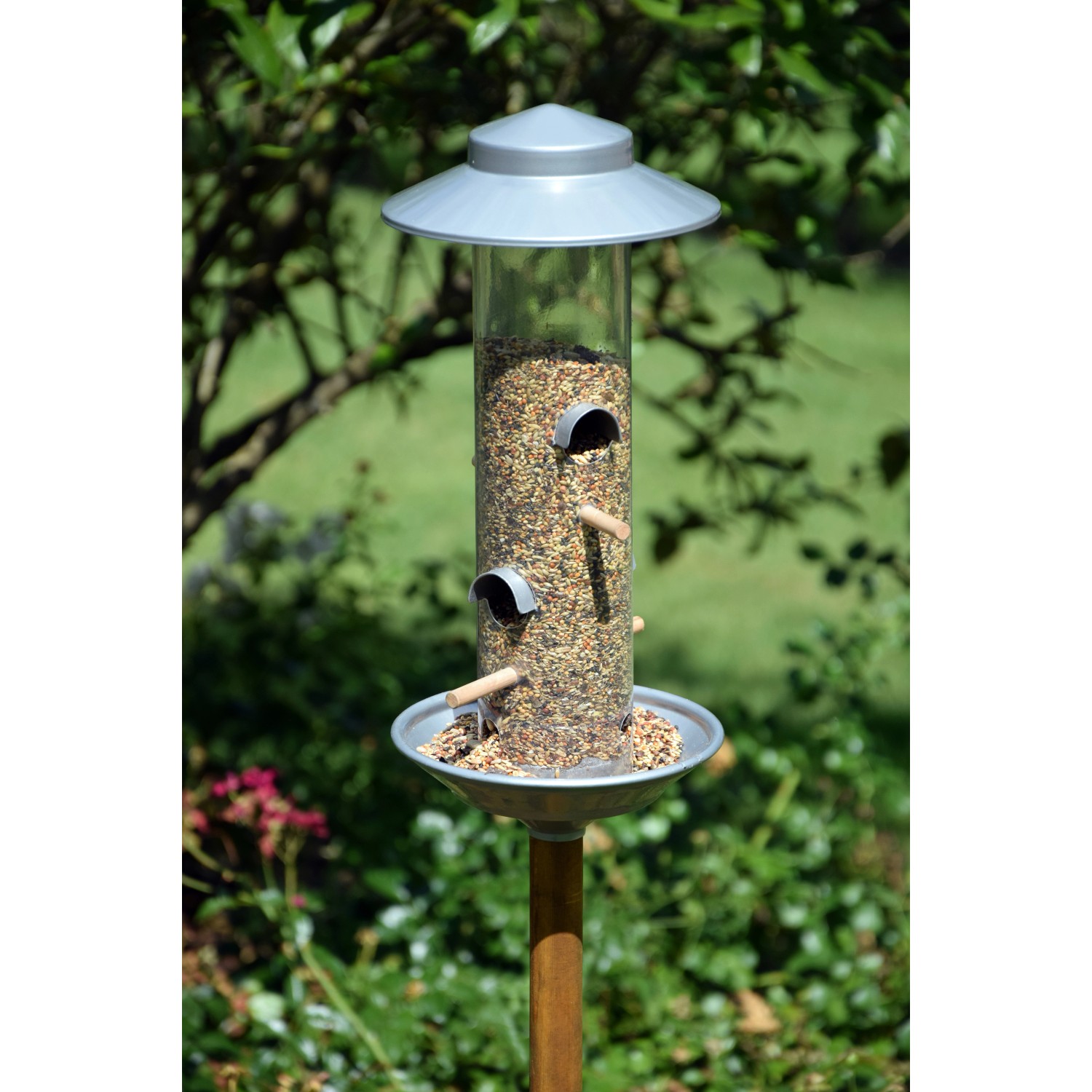 Silberner Dobar Stab-Vogelfutterspender mit Ständer im Garten. Vogelfutter ist sichtbar.