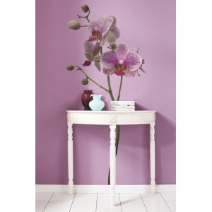 Deko-Sticker Orchidee (100x70 cm) an lila Wand über weißem Tisch mit Deko.