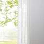 Weißer, blickdichter Schlaufenschal (300x135 cm) von mydeco vor Fenster.