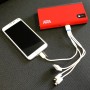 Mini Lithium Power Pack lädt Smartphone. Rote Powerbank mit LED-Leuchte und Ladekabel.