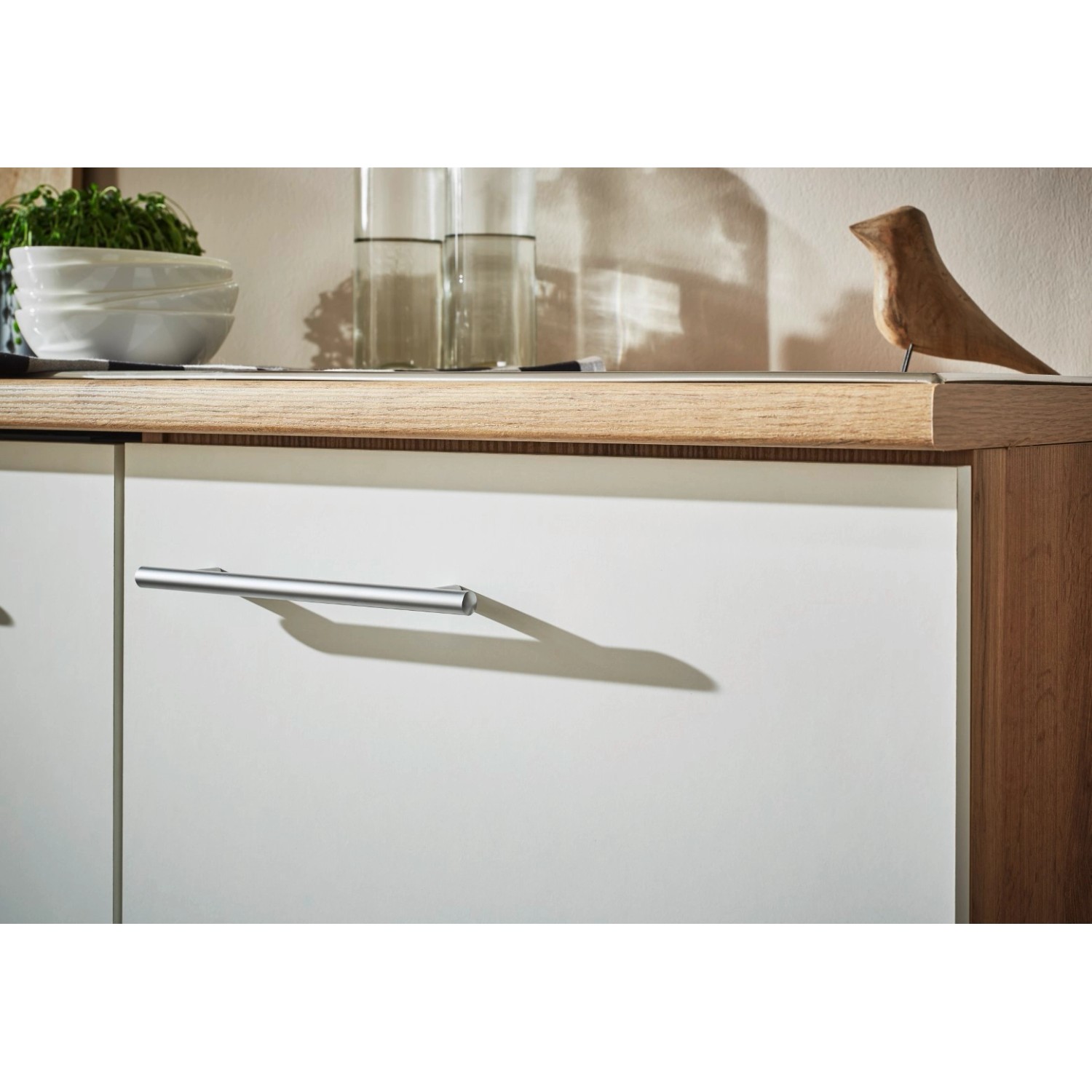 Detailansicht: Weiße Respekta Inselküche Hilde mit Metallgriffen und Holzarbeitsplatte.