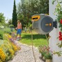 Hozelock Schlauchtrommel Auto Reel 30m im Einsatz: Frau bewässert Garten mit automatischer Schlauchbox.