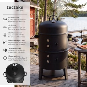 Schwarze Tectake Räuchertonne 3-in-1 zum Grillen, Räuchern, Garen mit Thermometer und 2 Rosten auf Holzterrasse am See.