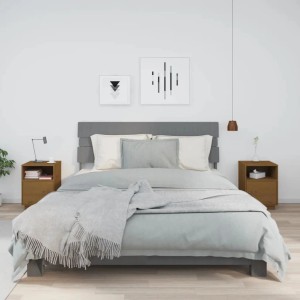 Set aus 2 honigbraunen Nachttischen aus Kiefernholz (40x34x55cm) neben einem Bett.