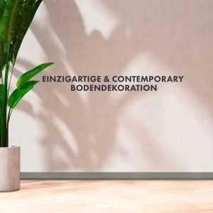 Graue, selbstklebende KARAT Sockelleiste Oslo (10m) im Raum mit Holzboden und Pflanze.