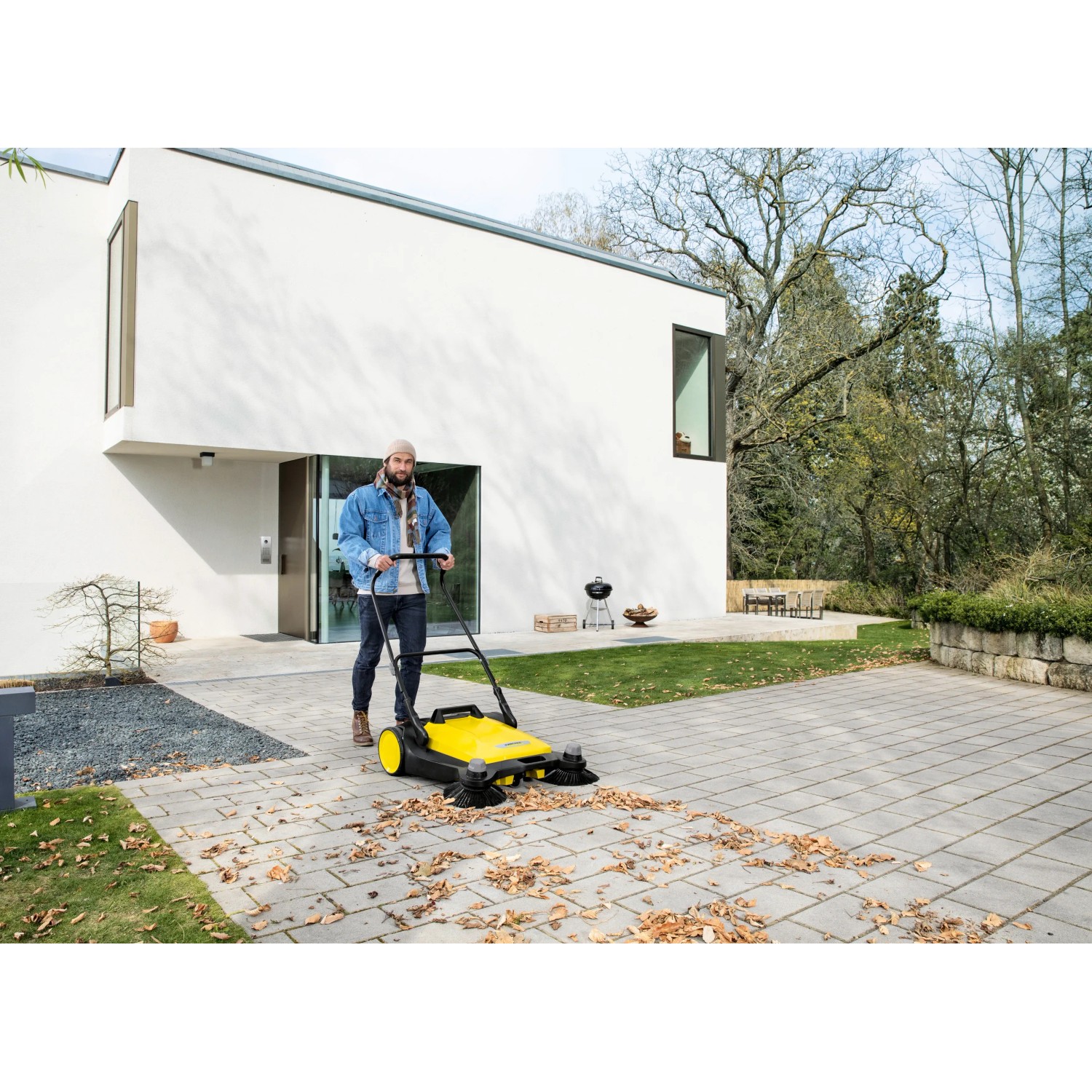 Gelbe Kärcher Kehrmaschine S6 Twin im Einsatz zum Laub kehren auf einer gepflasterten Fläche.