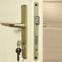 Detailaufnahme: Goldener Türgriff mit Schlüssel und Schloss eines Weka Holz-Gartenhauses.