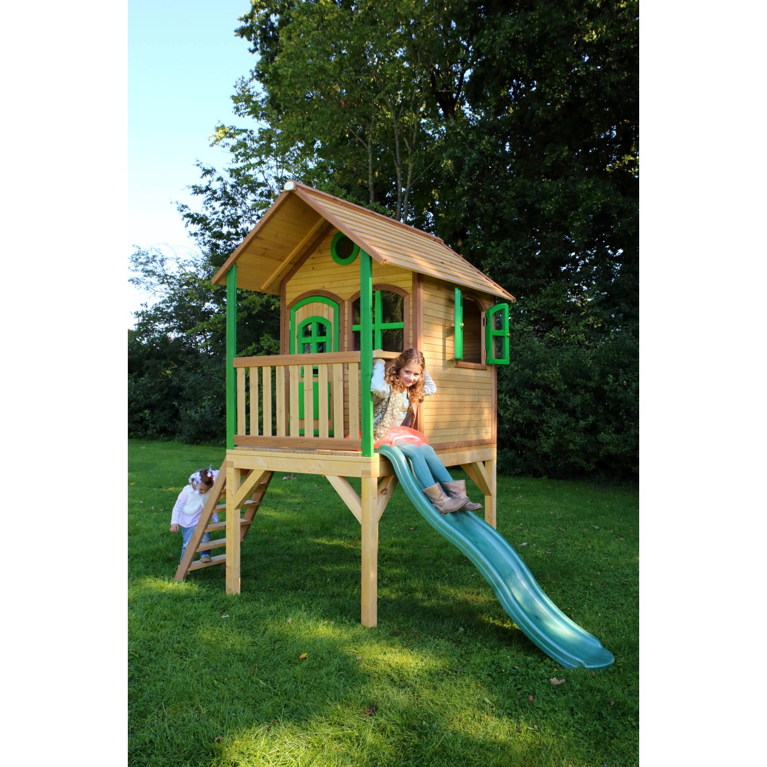 Spielhaus Laura mit Leiter, Rutsche und spielenden Kindern im Garten.
