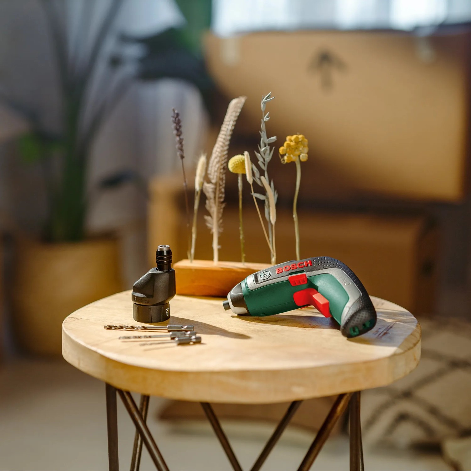 Bosch IXO 7 Akkuschrauber Set mit Winkelaufsatz, Exzenteraufsatz und Bits auf einem Tisch.