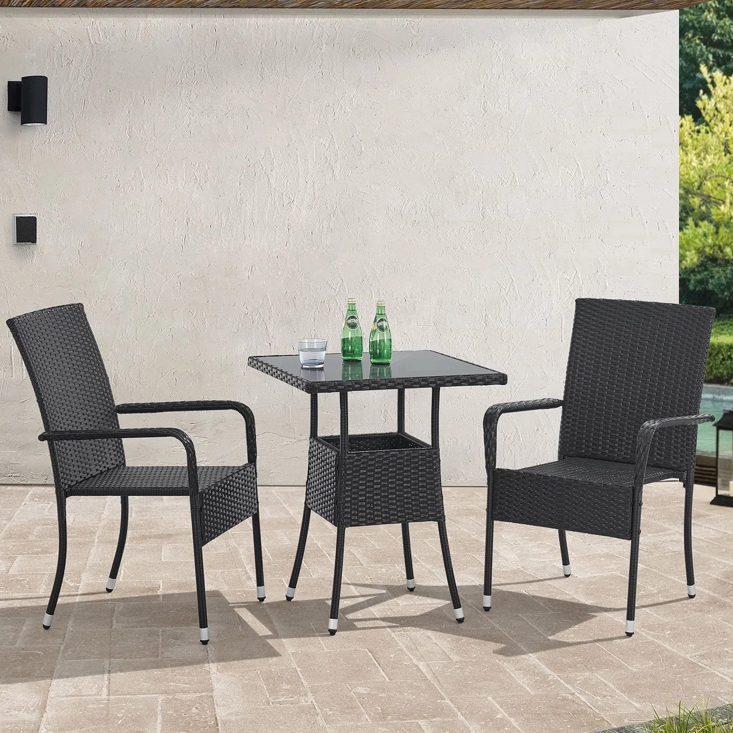 Quadratischer, schwarzer Polyrattan Gartentisch Yoro (60x60 cm) mit zwei Stühlen auf einer Terrasse.