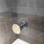 Detailaufnahme: Chromfarbener Duschkopf an grauer Wand im Badezimmer.