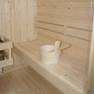 Innenansicht der Artsauna Cube Fasssauna Nolvik L mit Holzbänken und Sauna-Zubehör.