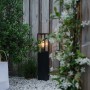 Schwarze, industrielle QAZQA Stehleuchte Charlois (80 cm) im Garten, mit warmem Licht.