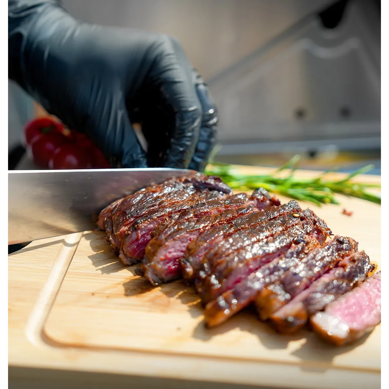 Angeschnittenes Steak vom Taino Platinum Gasgrill auf Holzbrett mit Messer und Hand.