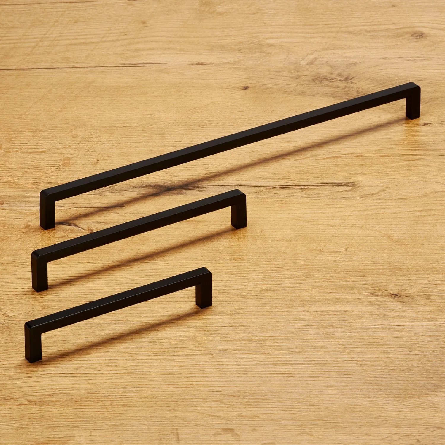 Drei schwarze, matte SOTECH BLACKLINE IX Möbelgriffe aus Aluminium auf Holz. Modernes Design, verschiedene Längen.