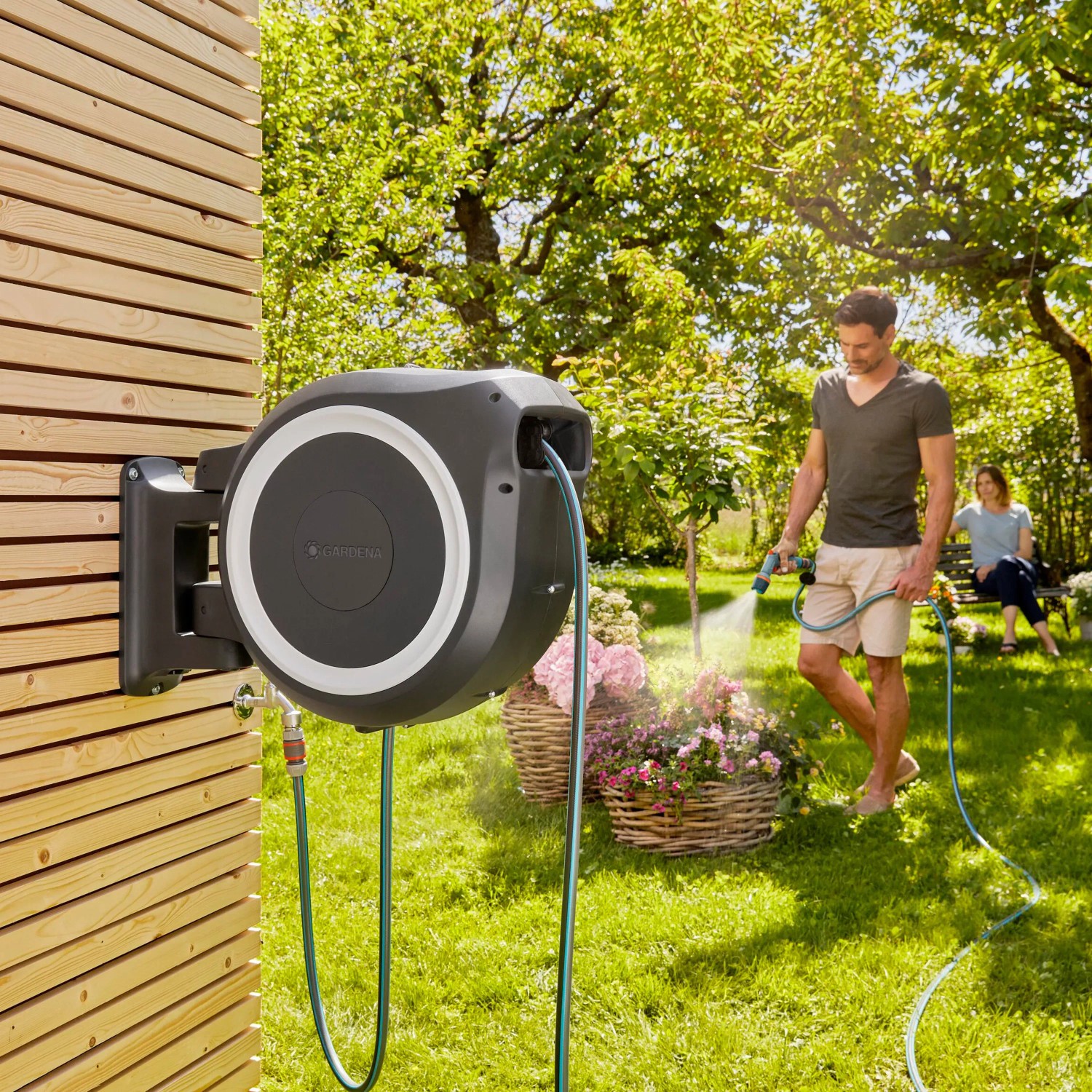Gardena Wand-Schlauchbox XL 35 m mit Comfort Reinigungsspritze im Einsatz im Garten.