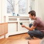 Mann misst mit Bosch UniversalTemp Infrarot-Thermometer Temperatur an Heizkörper.