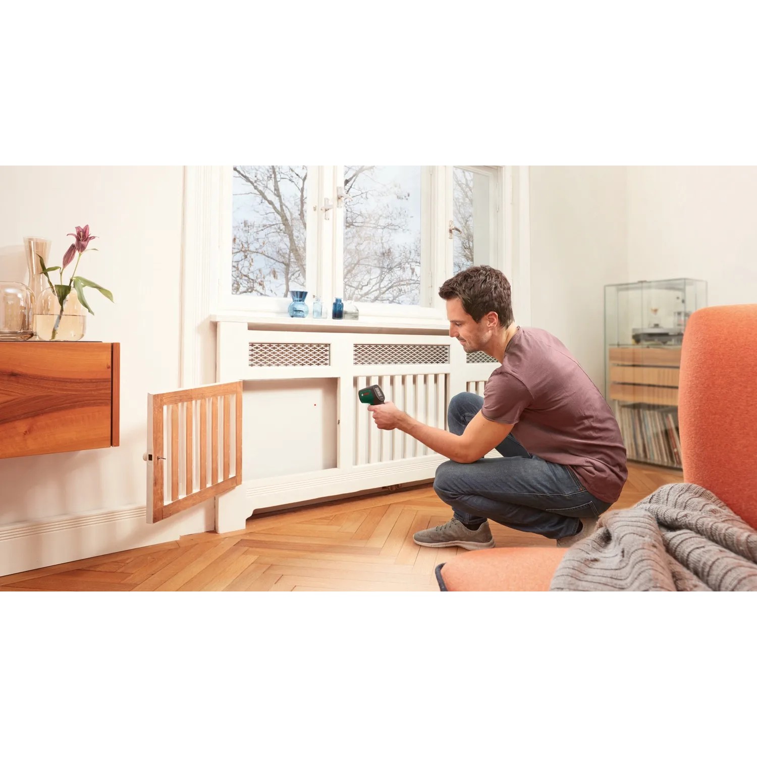 Mann misst mit Bosch UniversalTemp Infrarot-Thermometer Temperatur an Heizkörper.